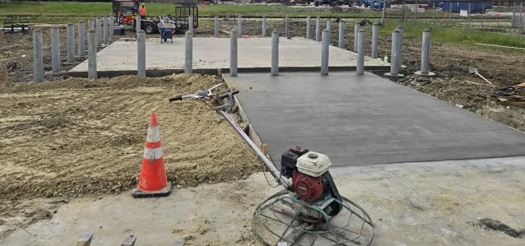 Power trowel finishing fresh concrete slab with structural columns