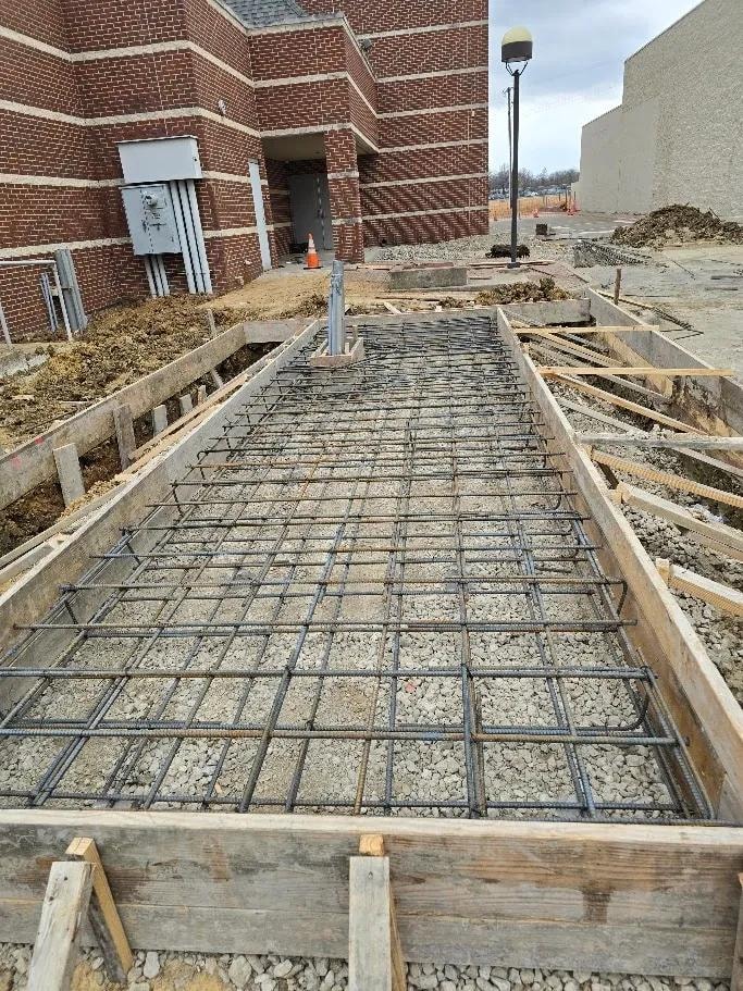Rebar grid and wood formwork for sidewalk pour next to brick building