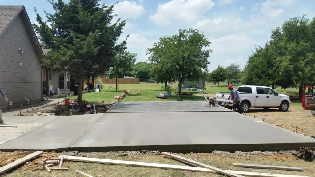 Fresh concrete driveway pour at rural home with crew finishing