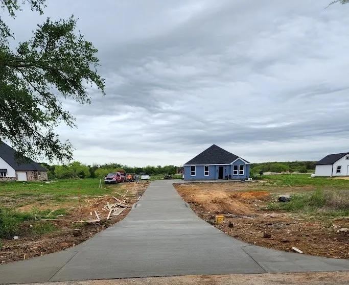 Long concrete driveway leading to new construction blue house