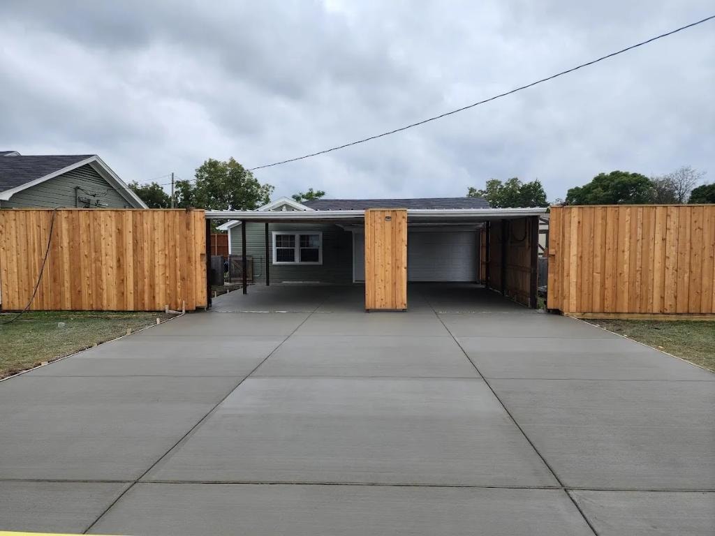 Wide concrete driveway with wood fence and detached garage