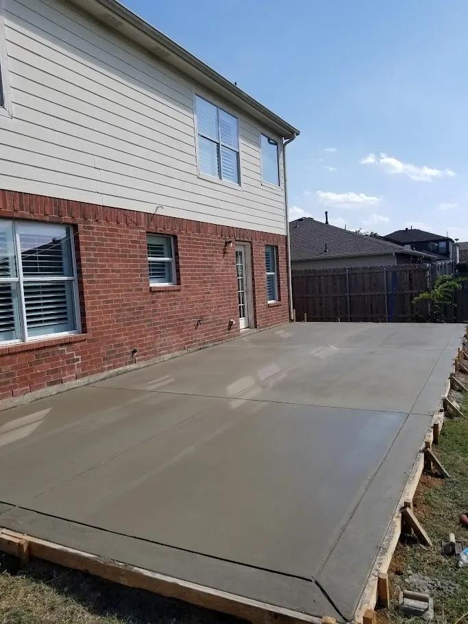Freshly poured concrete patio at brick and siding home