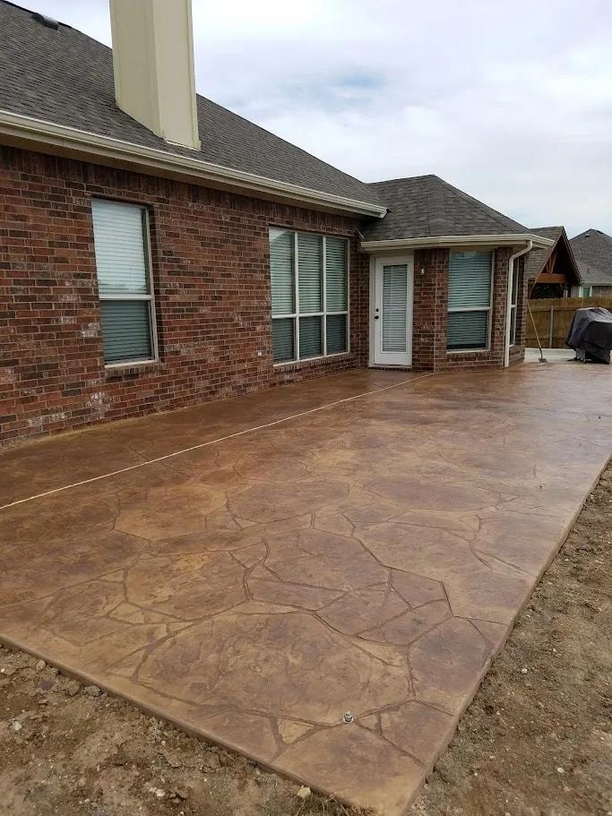 Stamped concrete patio with flagstone pattern at brick home
